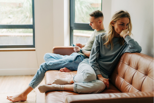 couple on couch looking frustrated woman is facing away